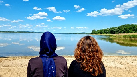 Zwei Frauen sitzen auf einer Bank an einem See